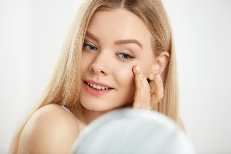 Eine schöne Frau mit langen blonden Haaren berührt ihr linkes Auge