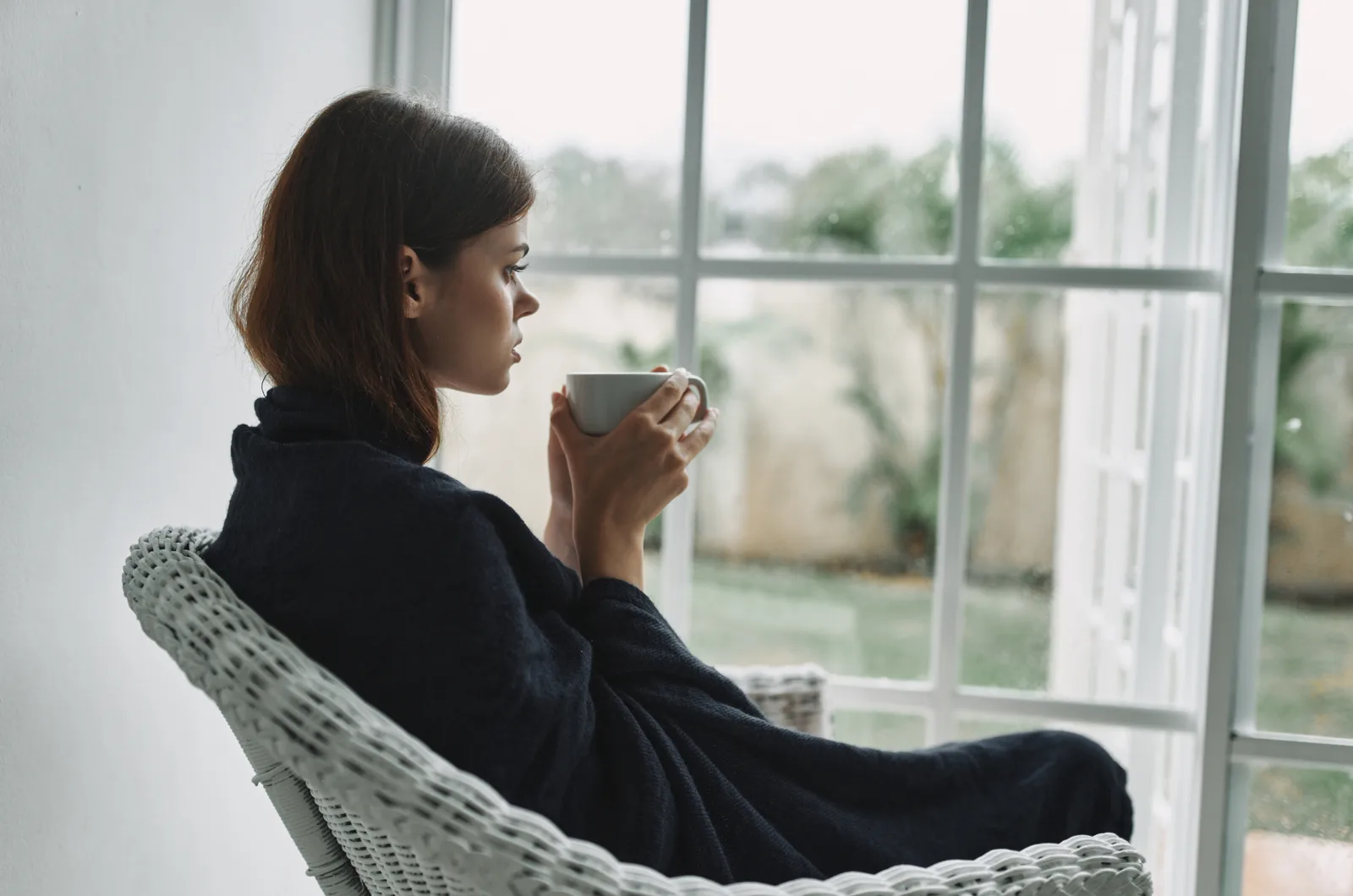 Frau sitzt auf Stuhl und trinkt Tee