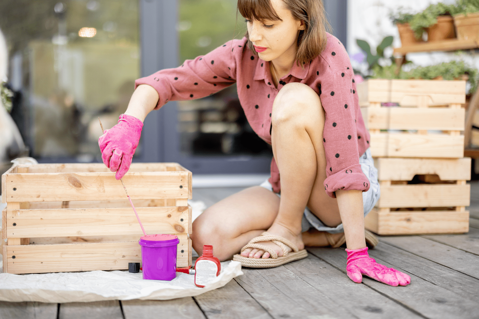 Junge Frau malt Holzkiste in rosa Farbe