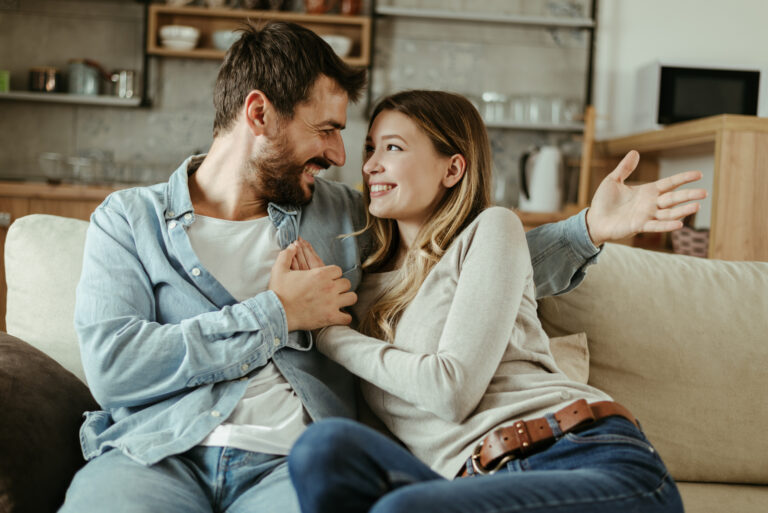 eine Frau in den Armen eines Mannes, während sie auf der Couch sitzen