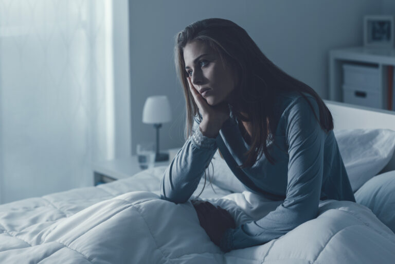 Die wache Frau sitzt im Bett