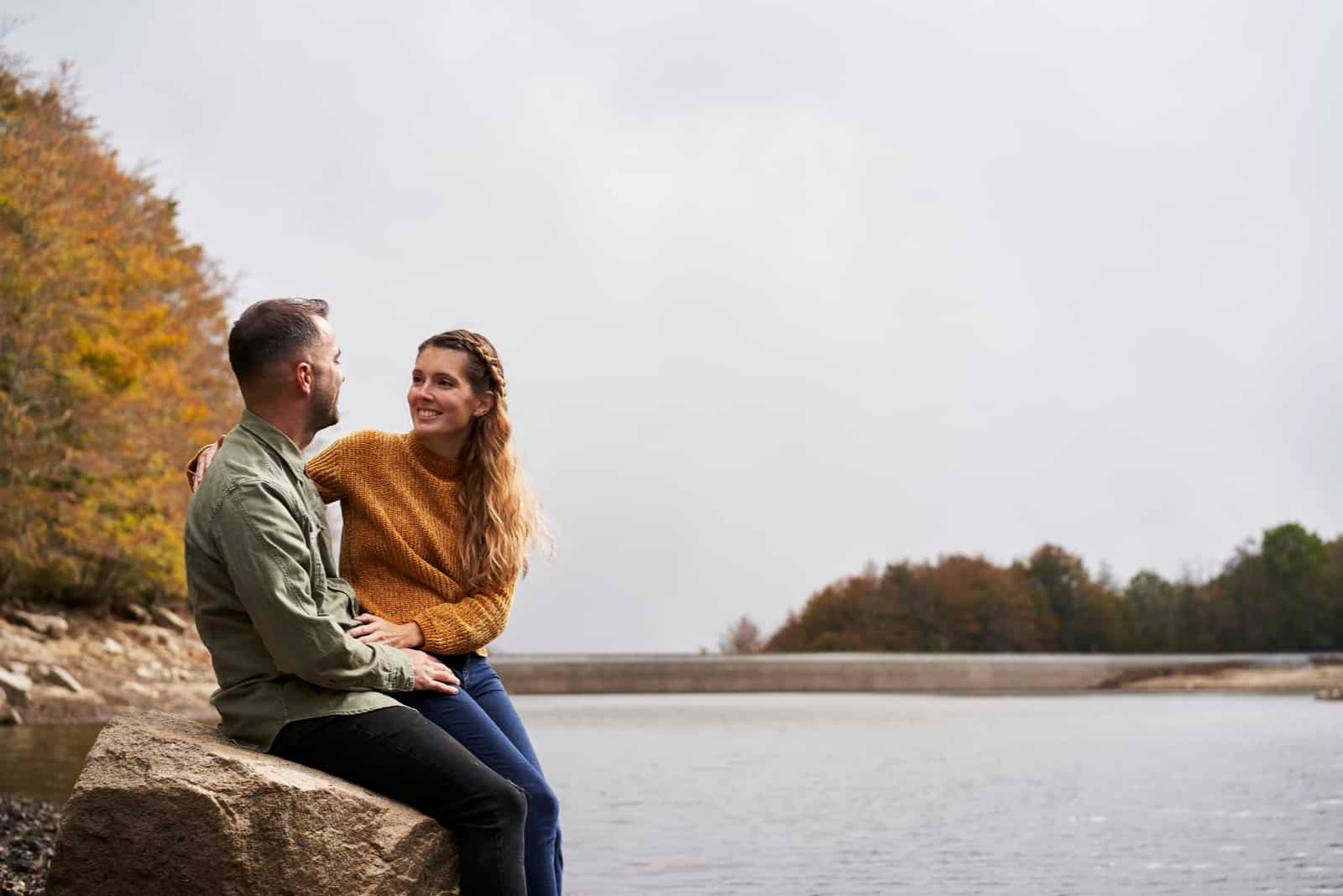 Paar sitzt auf einem Felsen vor einem See