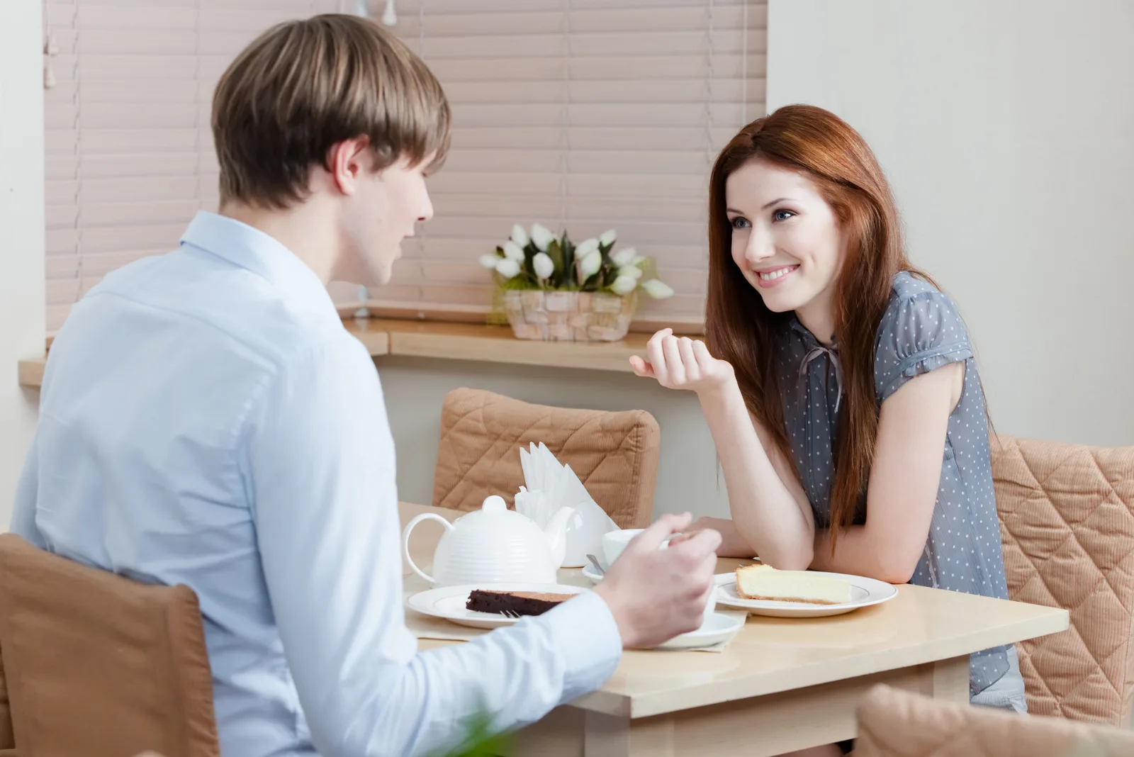 Eine lächelnde Frau sitzt mit einem Mann am Tisch und sie unterhalten sich