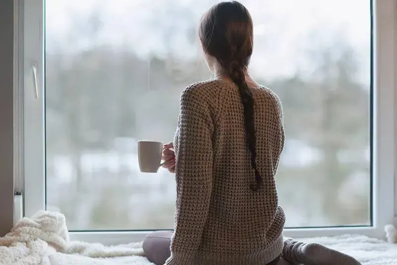 Frau mit Tasse am Fenster