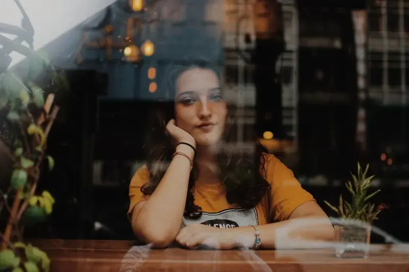 junge Frau sitzt im Cafe am Fenster