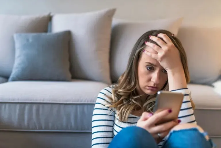 besorgte Frau, die auf das Telefon schaut