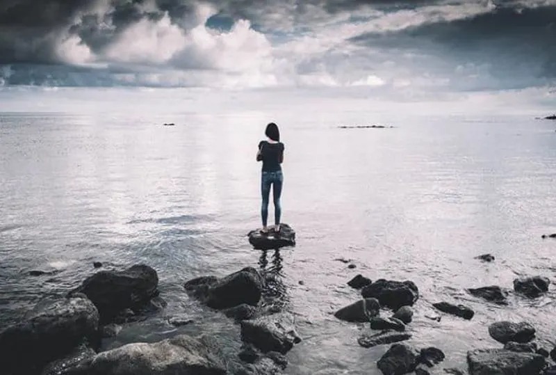 Frau steht auf dem Meeresfelsen