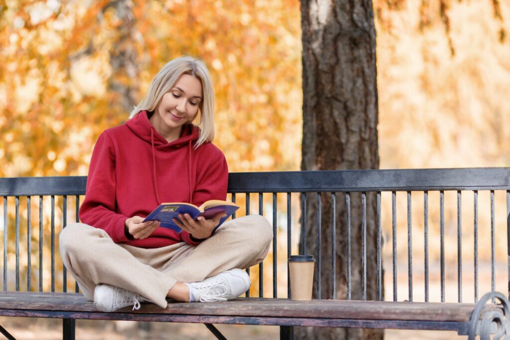 Ein Mädchen sitzt auf einer Bank und liest ein Buch