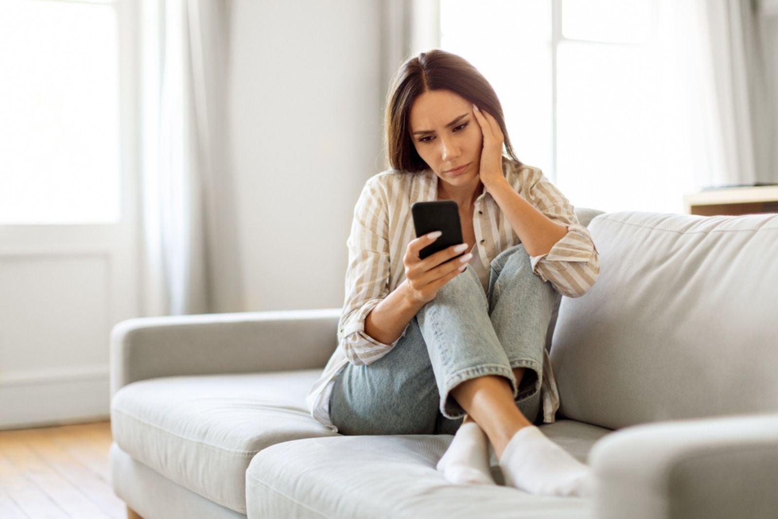 besorgte Frau, die auf das Telefon schaut