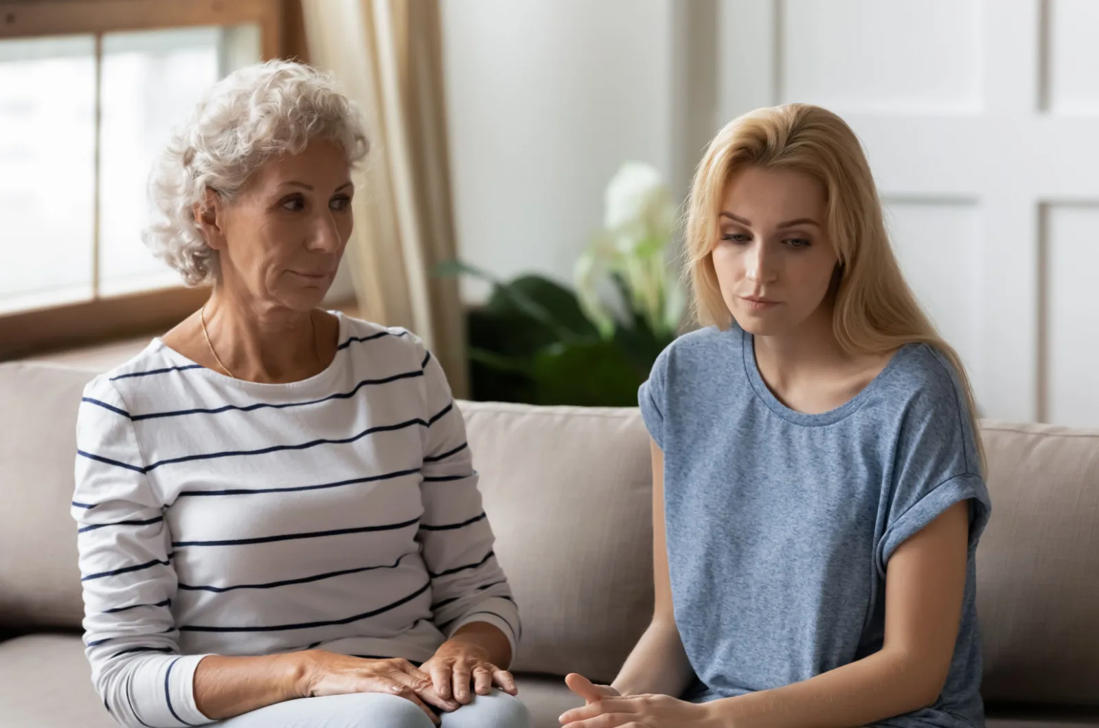 Aeltere Mutter und Tochter sitzen auf der Couch