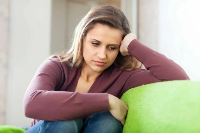 traurig denkende Frau auf der Couch