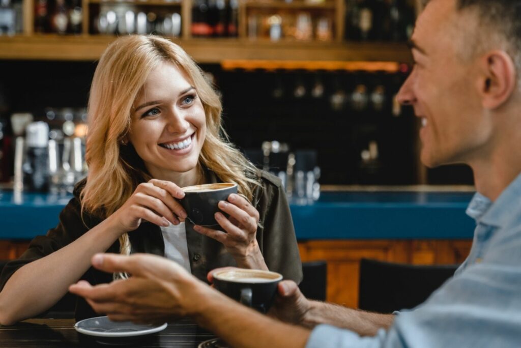 Ein lächelndes Mädchen sitzt in einem Café neben einem Mann und sie reden