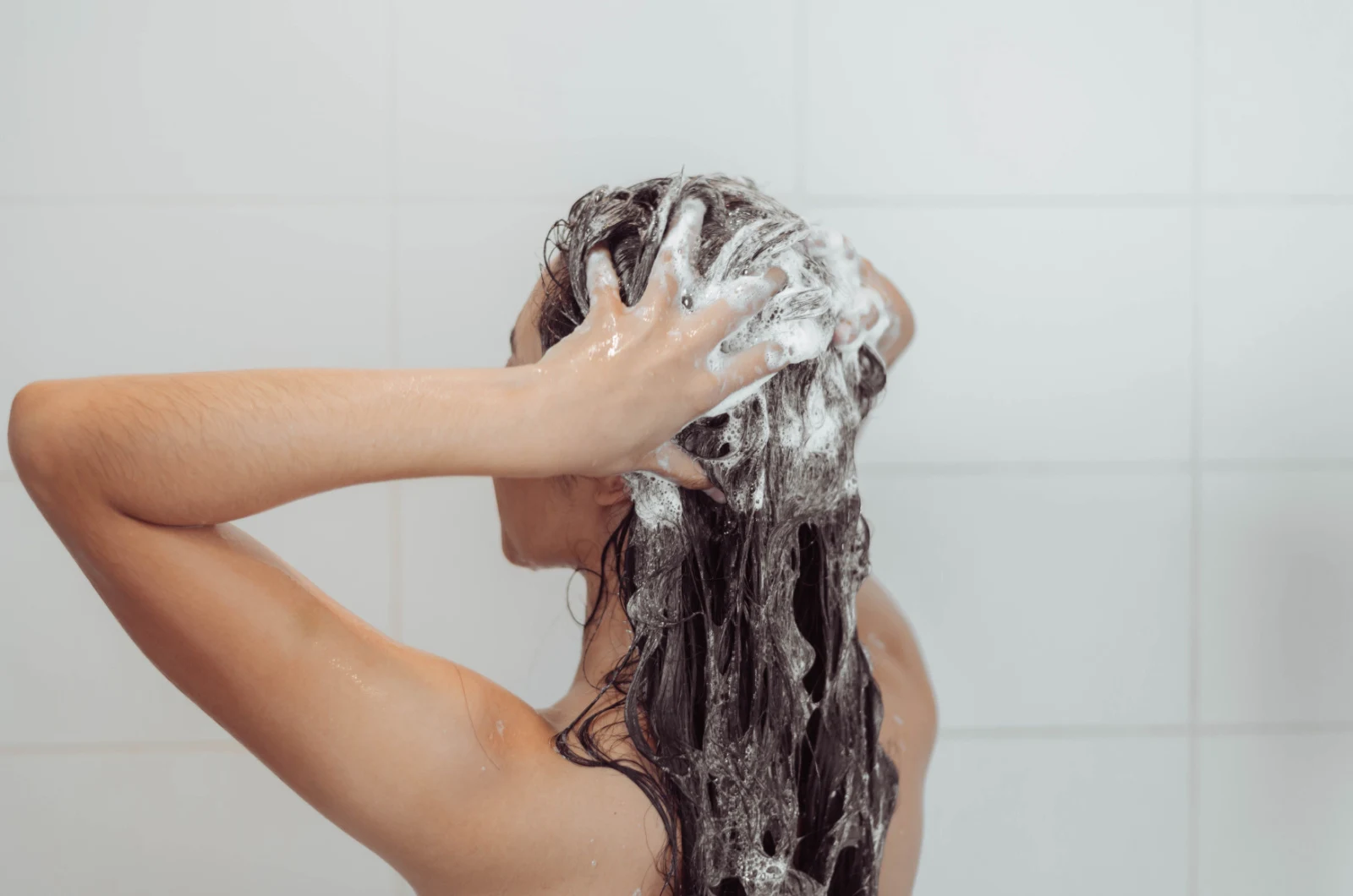 Frau wäscht Haare in der Dusche