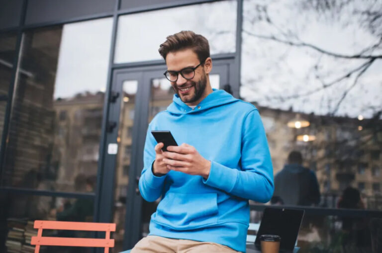Mann draußen, der sein Mobiltelefon benutzt