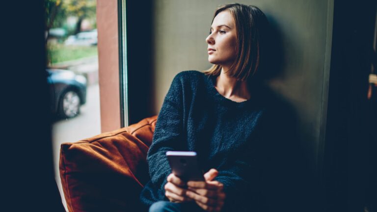 nachdenkliches Maedchen sitzt am Fenster