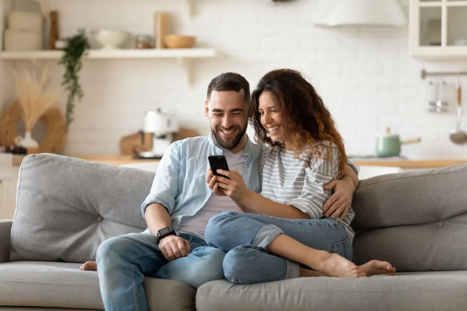 Paar sitzt auf der Couch und schaut aufs Telefon