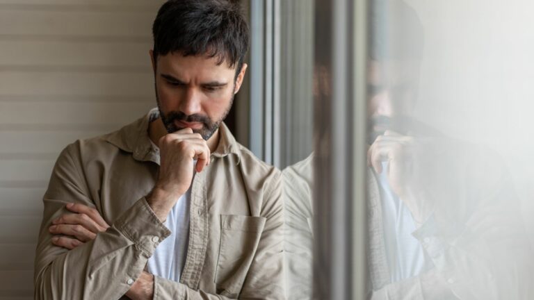 Ein nachdenklicher Mann steht am Fenster