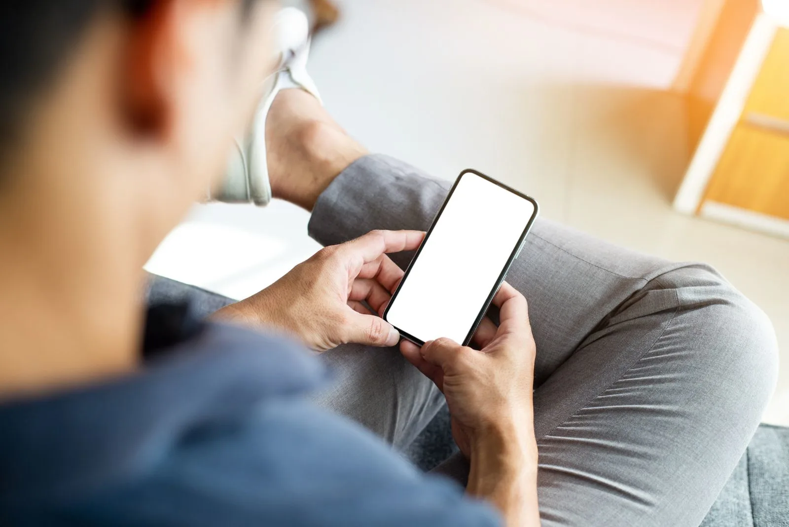 Ein Mann haelt ein Mobiltelefon in der Hand