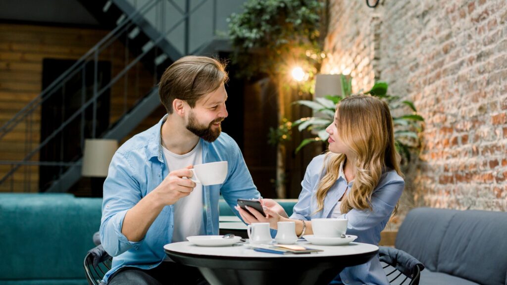 Ein Mann sitzt neben einer Frau in einem Café und sie unterhalten sich