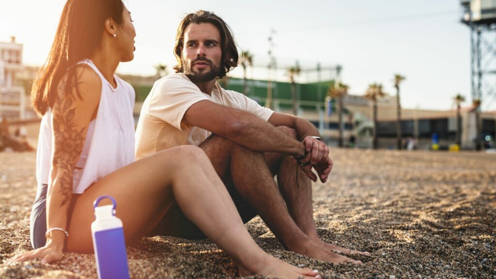 Ein Mann und eine Frau sitzen am Strand und unterhalten sich