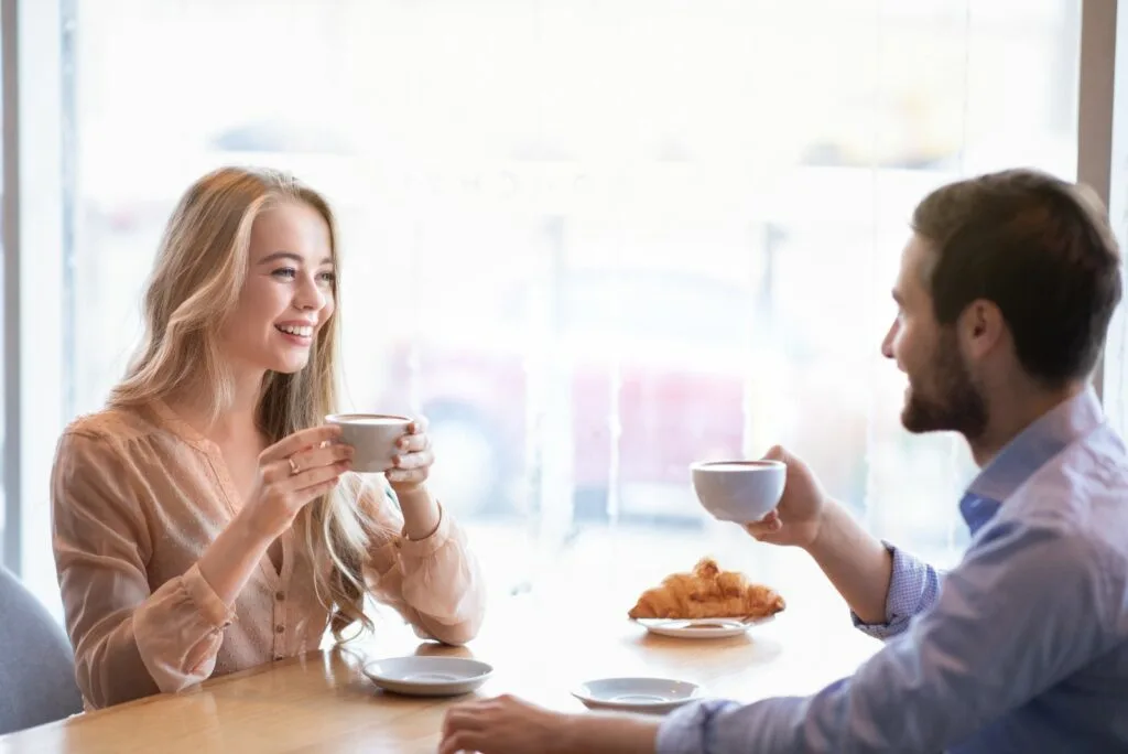 Ein Mann und eine Frau sitzen an einem Tisch und unterhalten sich beim Kaffee