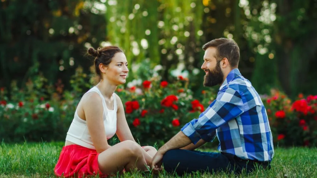 Ein Mann und eine Frau sitzen im Gras und unterhalten sich