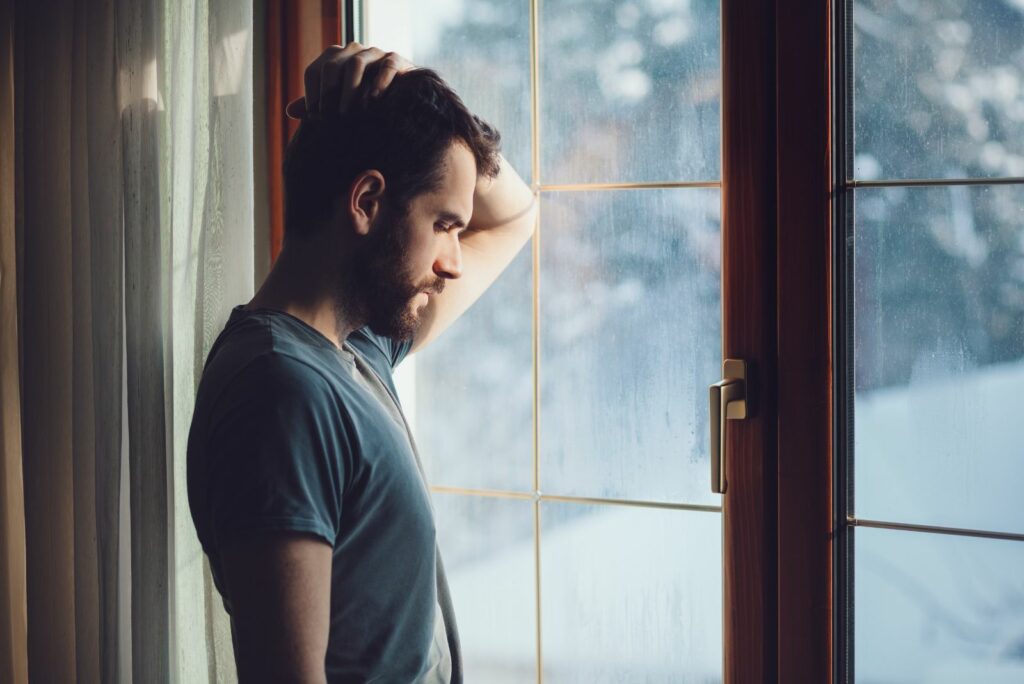 Ein junger Mann steht am Fenster