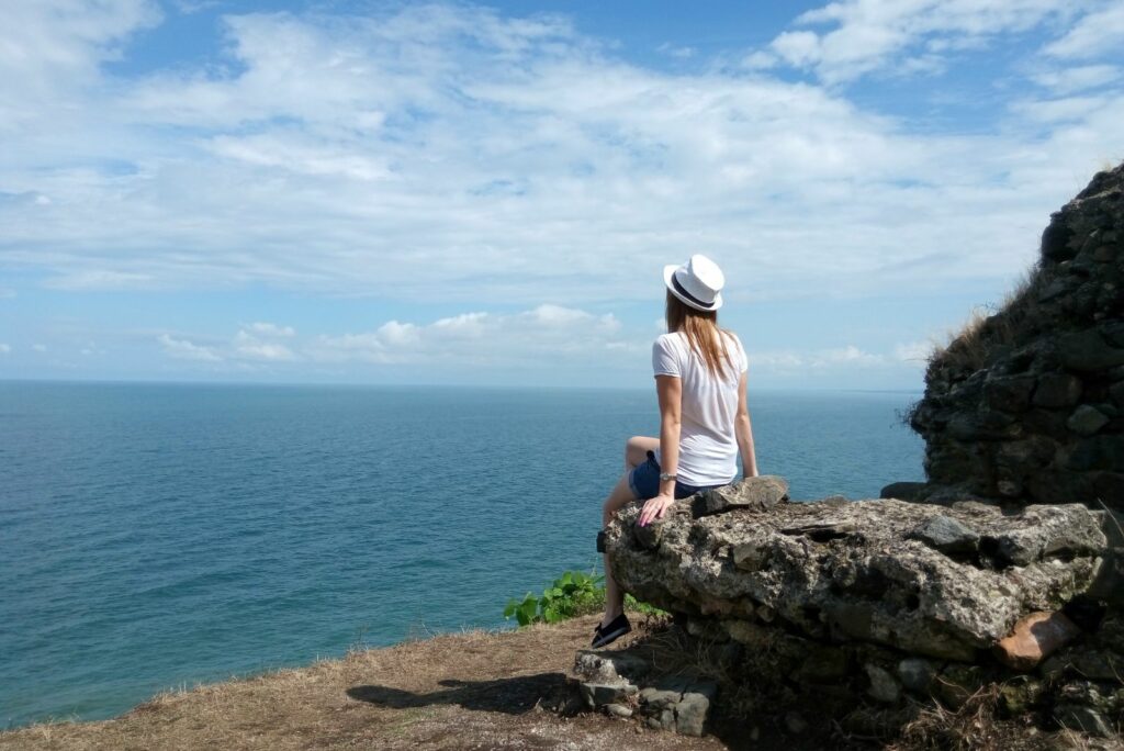 Eine Frau mit Hut sitzt auf einem Felsen