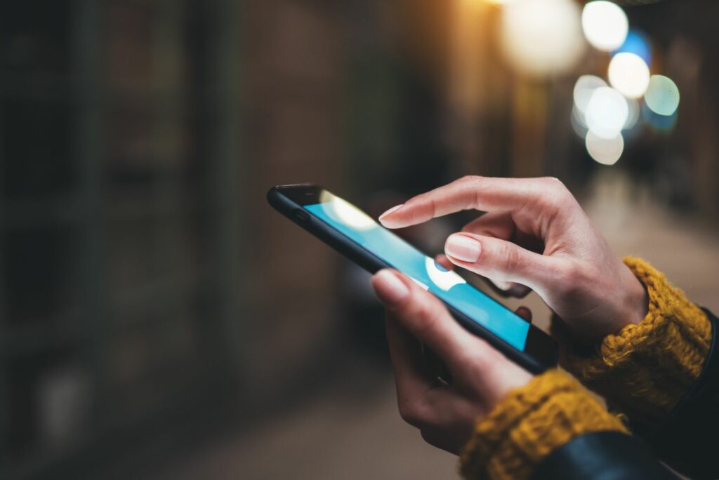 Eine Frau steht mit einem Mobiltelefon in der Hand auf der Straße