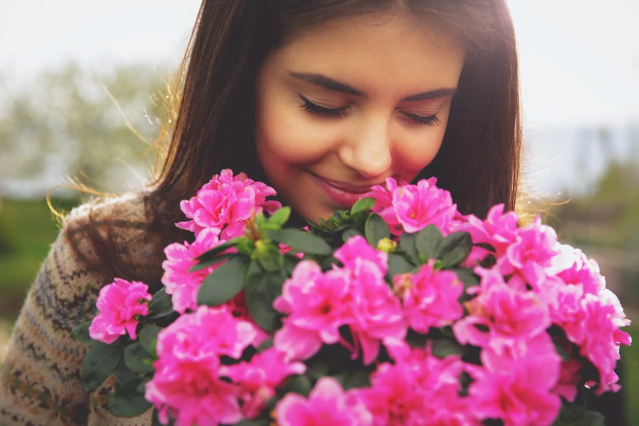 Frau schnueffelt an einer Blume