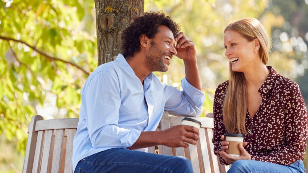 Laechelnder Mann, der beim Kaffee mit einer Frau spricht