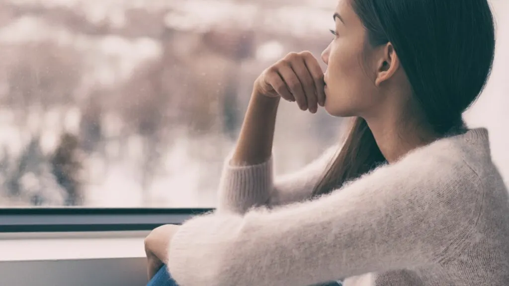 Nachdenkliche Frau sitzt am Fenster