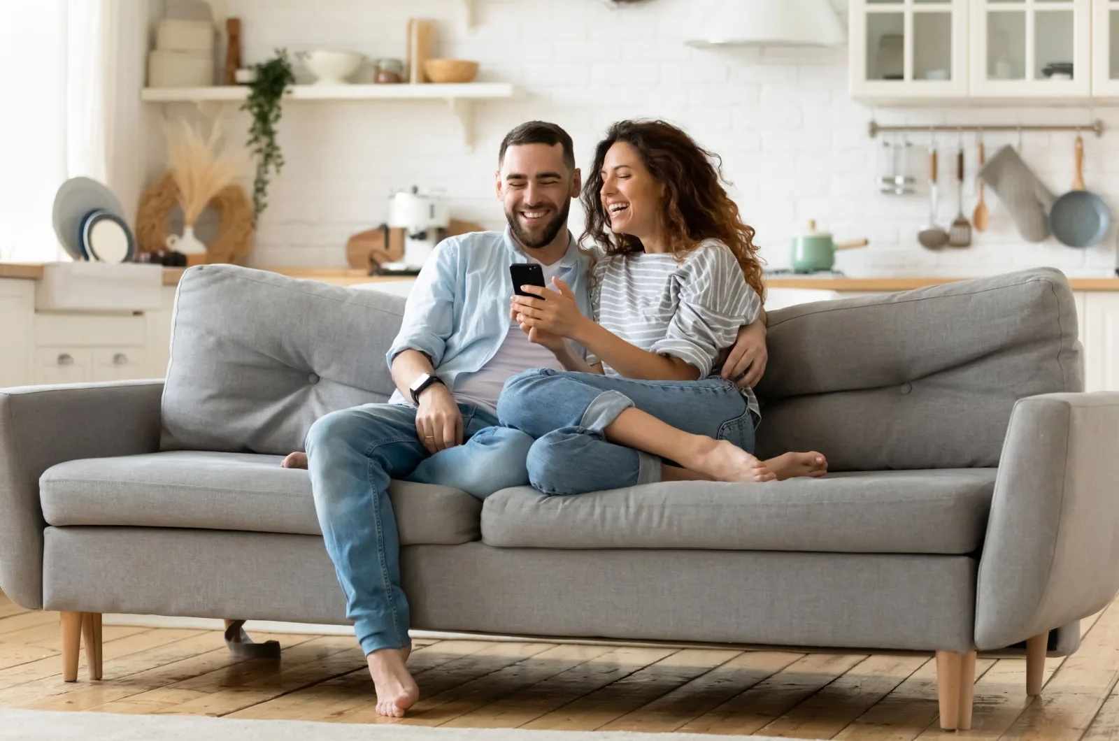 Paar sitzt auf der Couch und schaut aufs Telefon