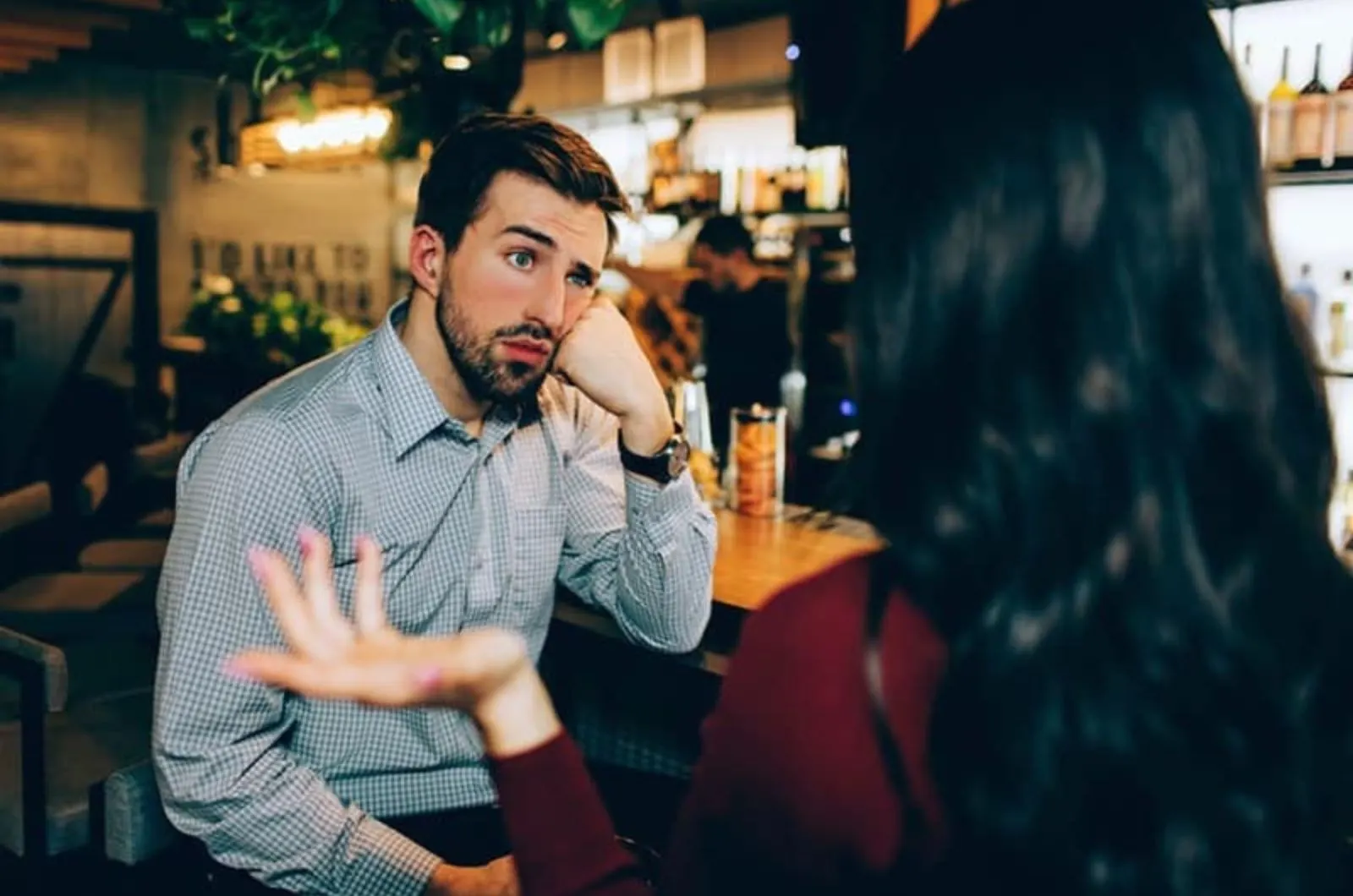 gelangweilter Mann hoert Frau in der Bar zu