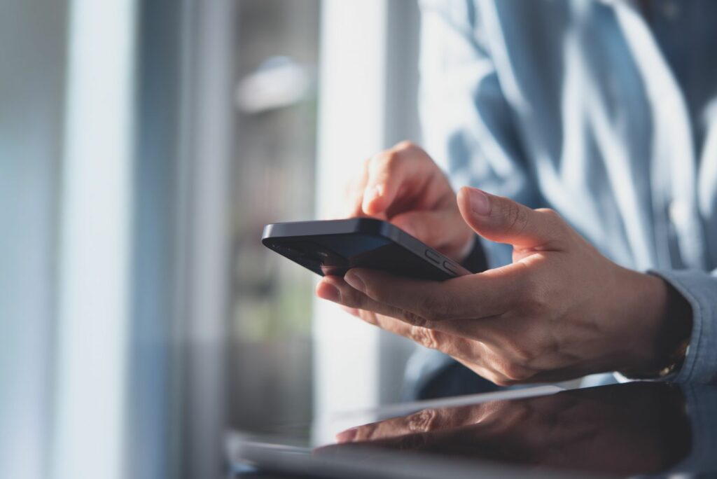 Ein Mann haelt ein Mobiltelefon in der Hand