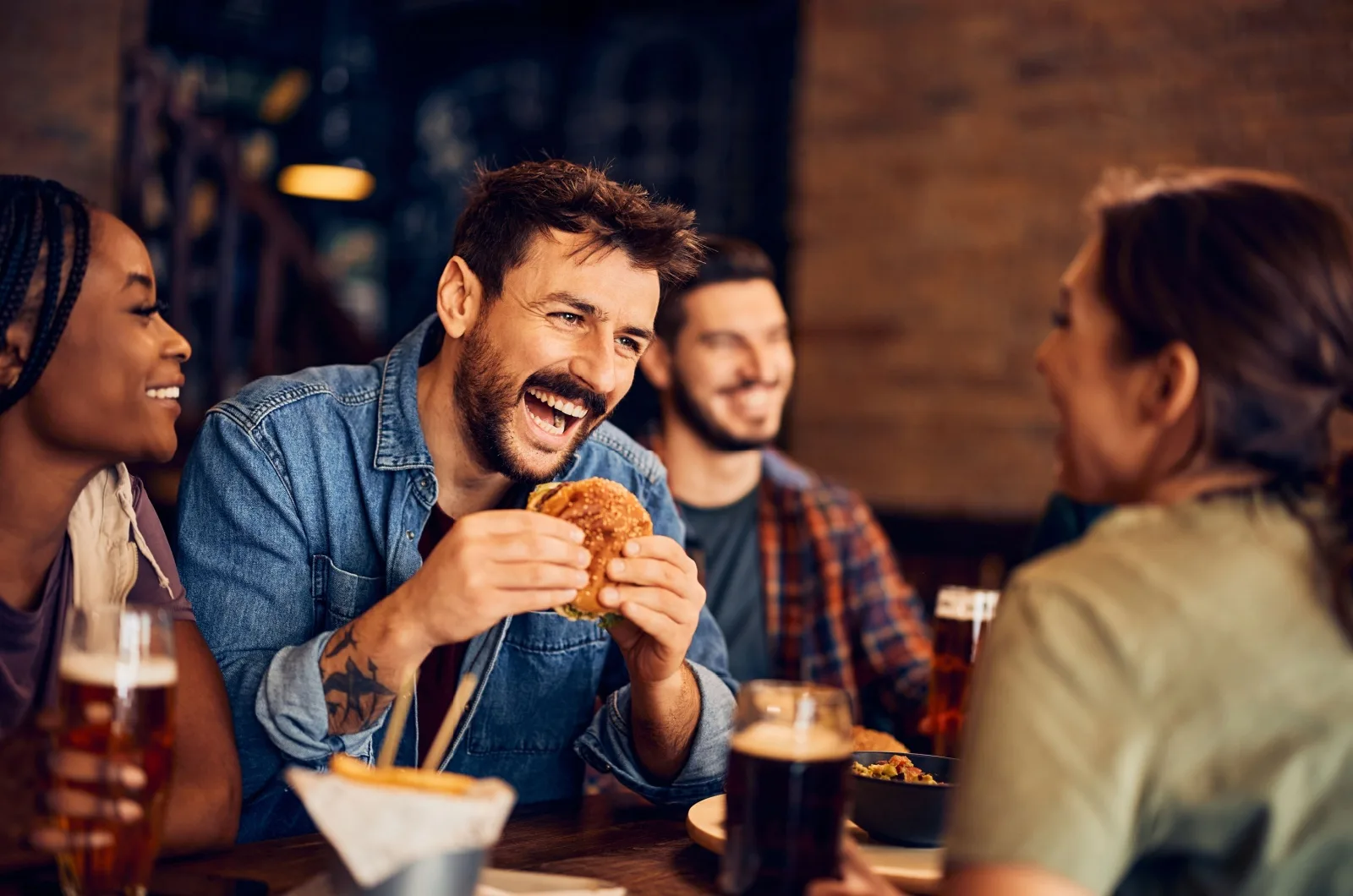 Froehlicher Mann, der mit Freunden Burger isst