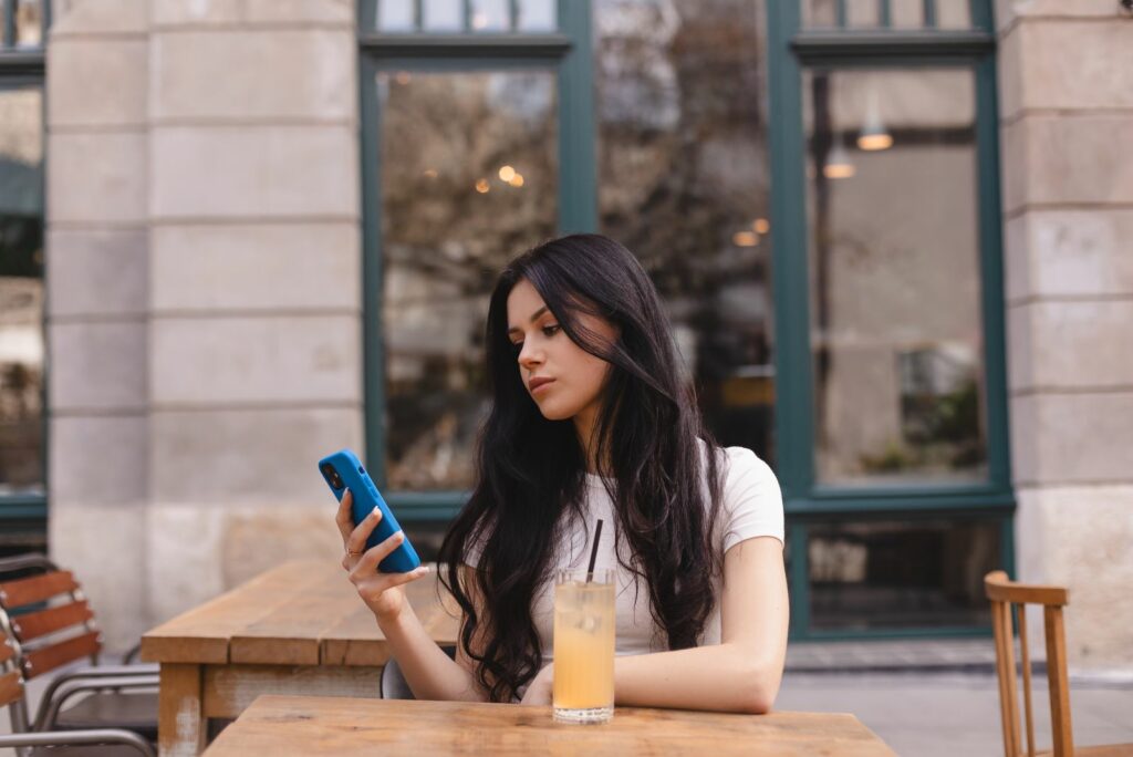 Die Frau sitzt am Tisch und tippt am Telefon