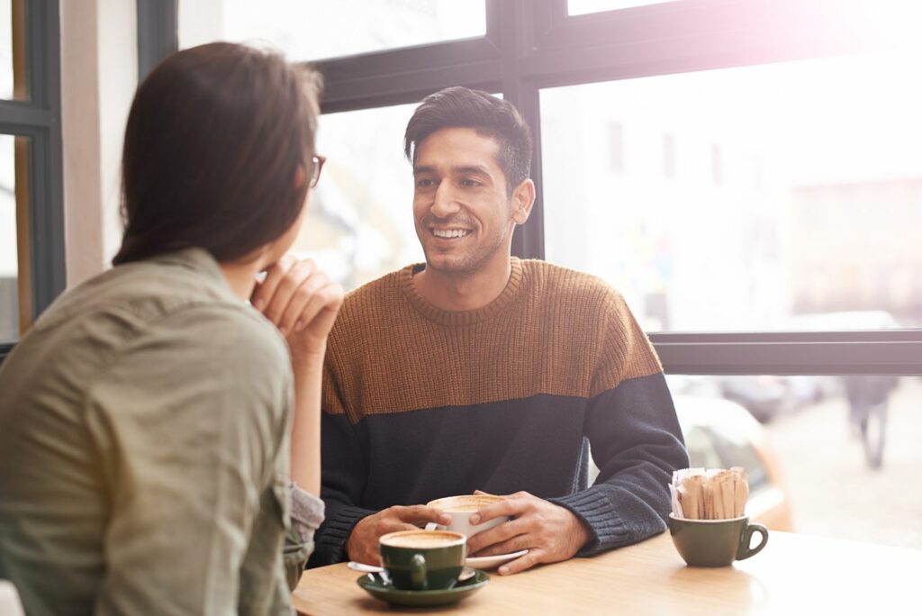 Ein laechelnder Mann spricht mit einer Frau in einem Café