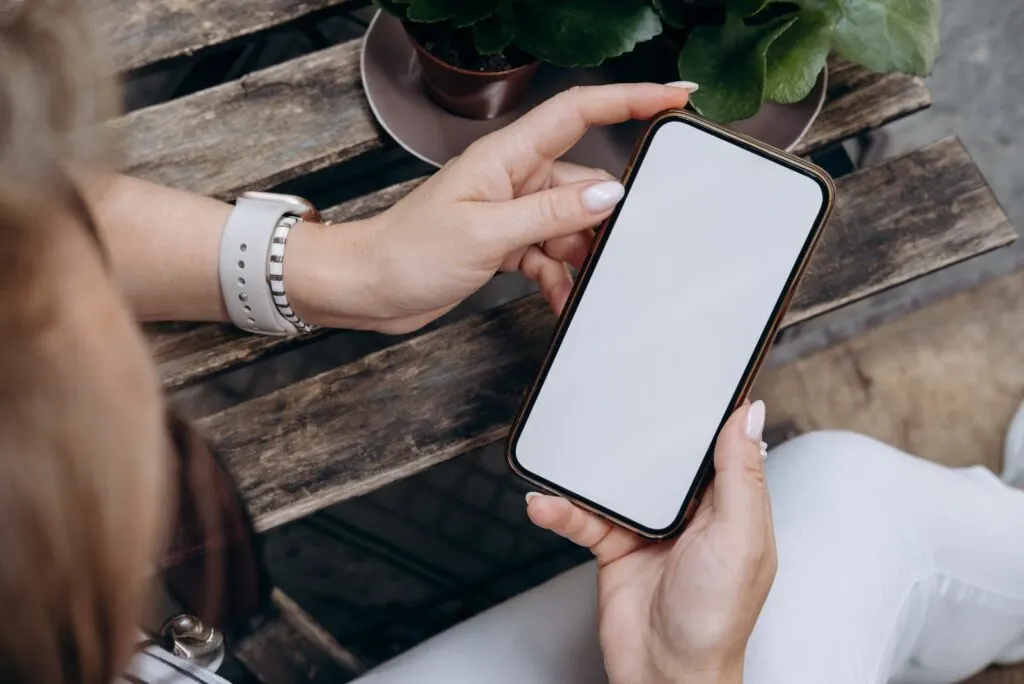 Eine Frau haelt ein Mobiltelefon in der Hand