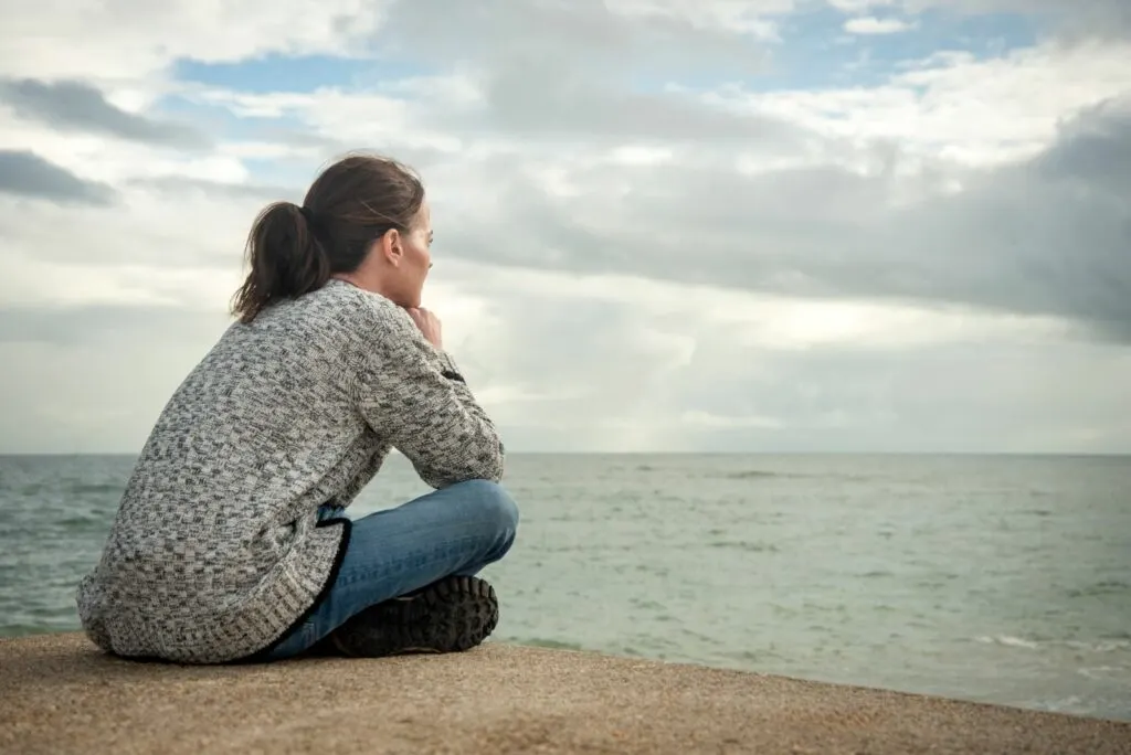 Eine Frau sitzt und blickt auf das Meer