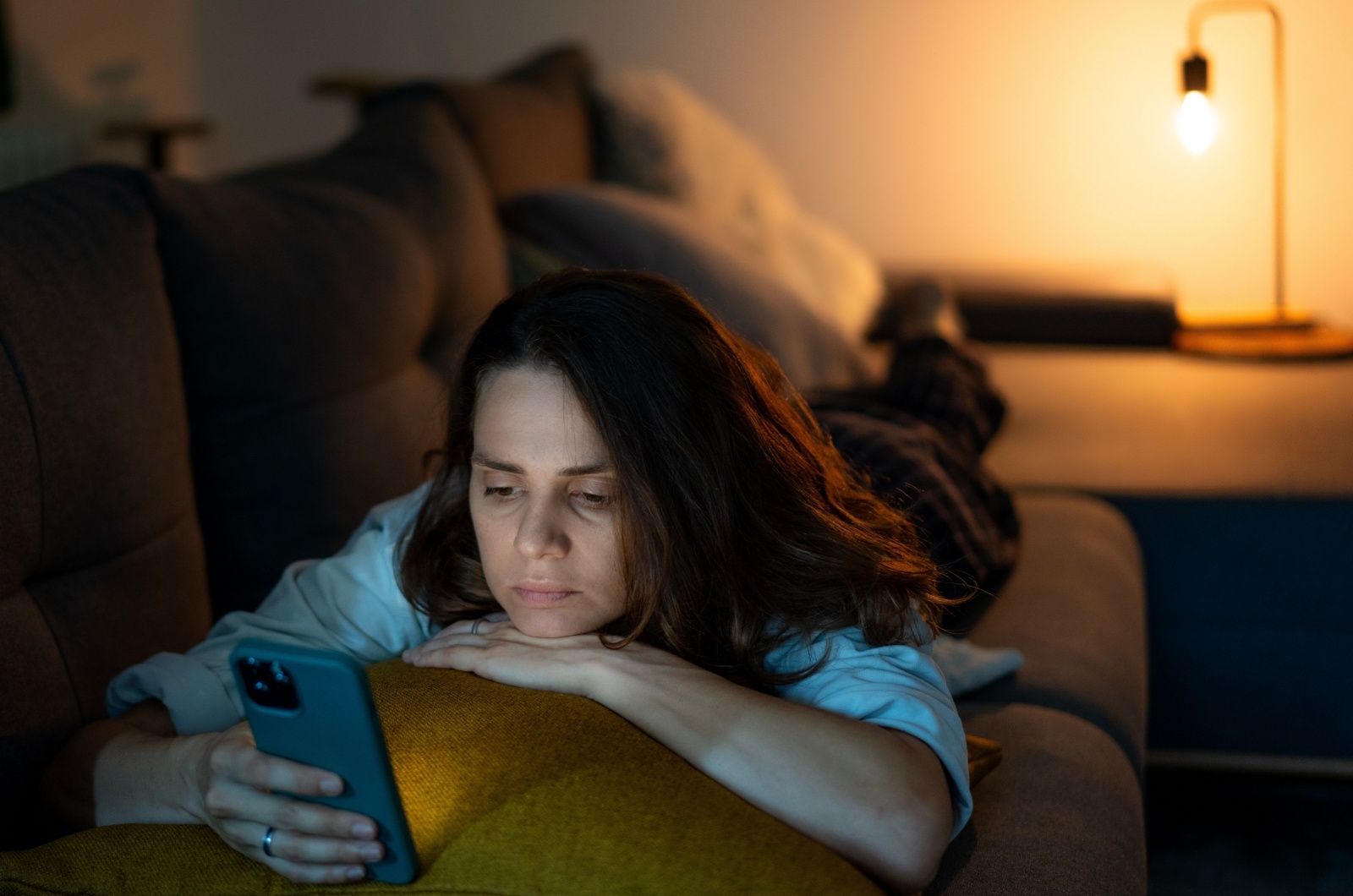 Frau liegt und benutzt ihr Telefon