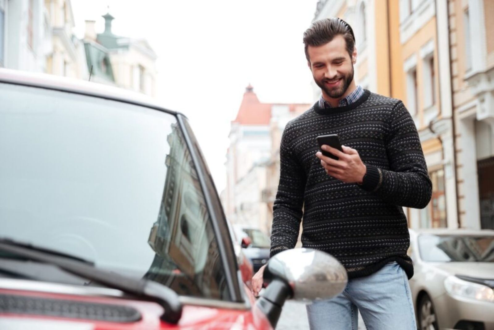 laechelnder Mann schaut auf Handy