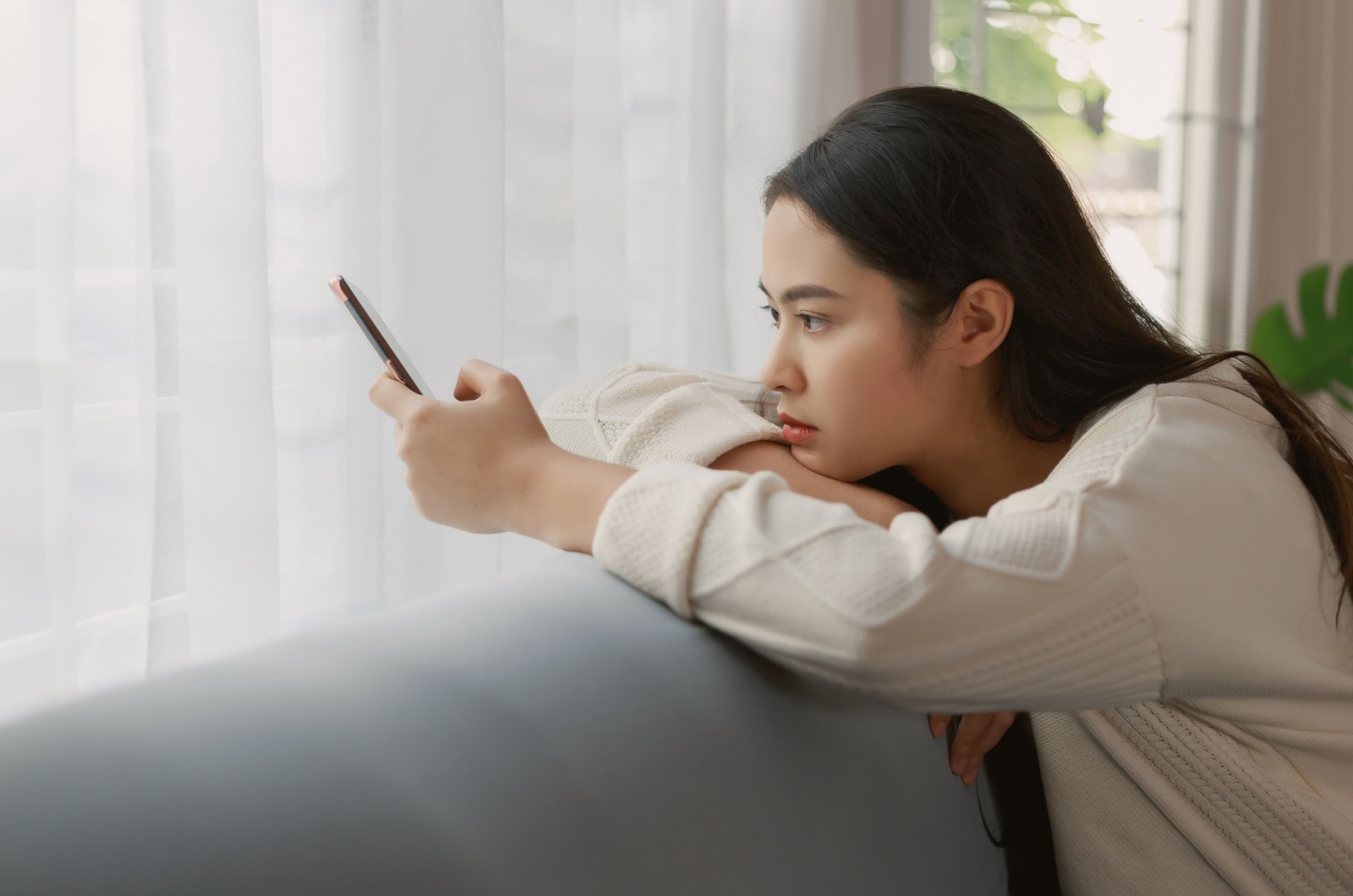 traurige Frau schaut aufs Telefon