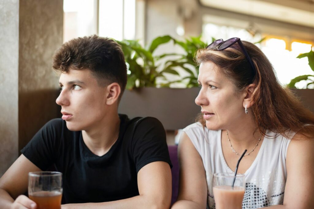 Die Frau sitzt neben ihrem Sohn und sie unterhalten sich