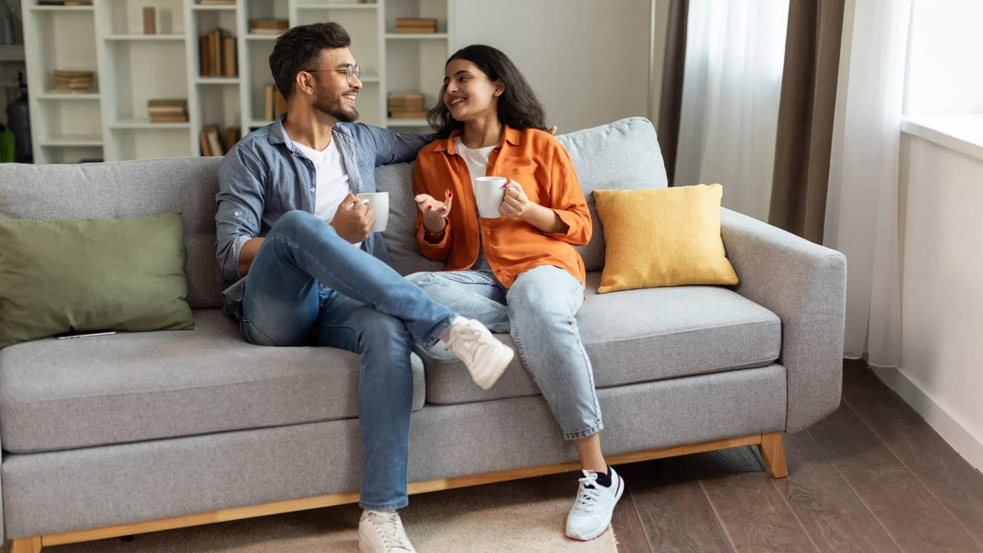 Ein Mann und eine Frau sitzen auf der Couch und unterhalten sich beim Kaffee