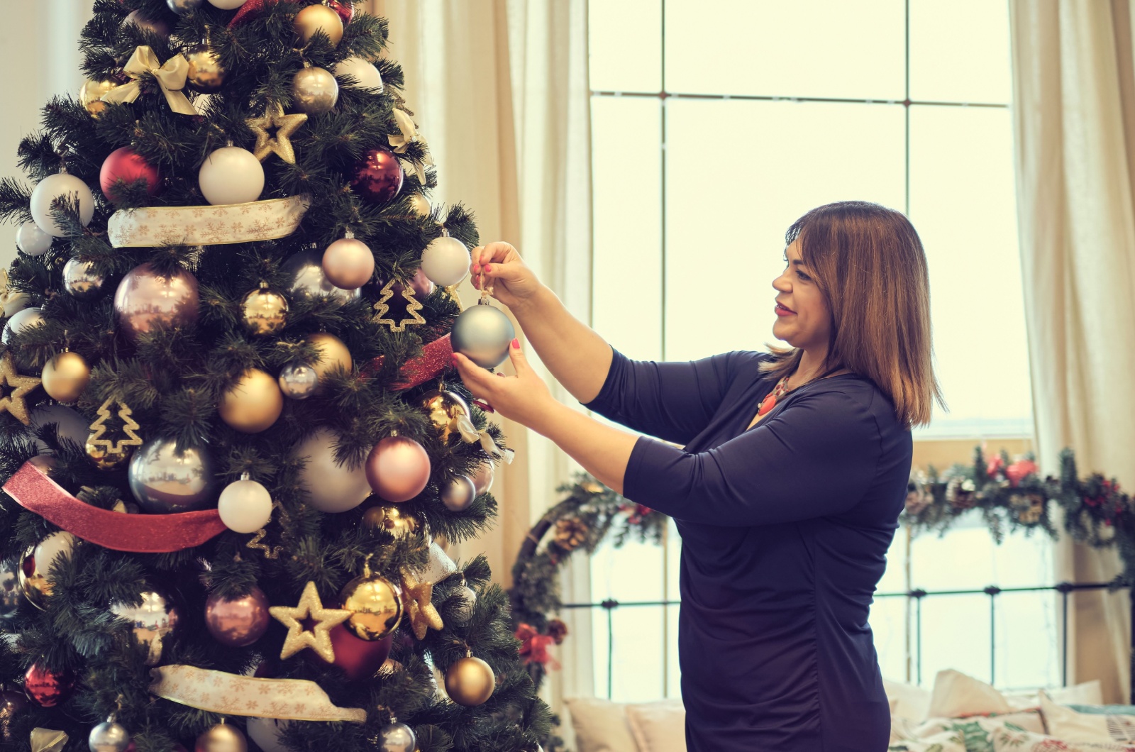 Frau schmueckt den Weihnachtsbaum