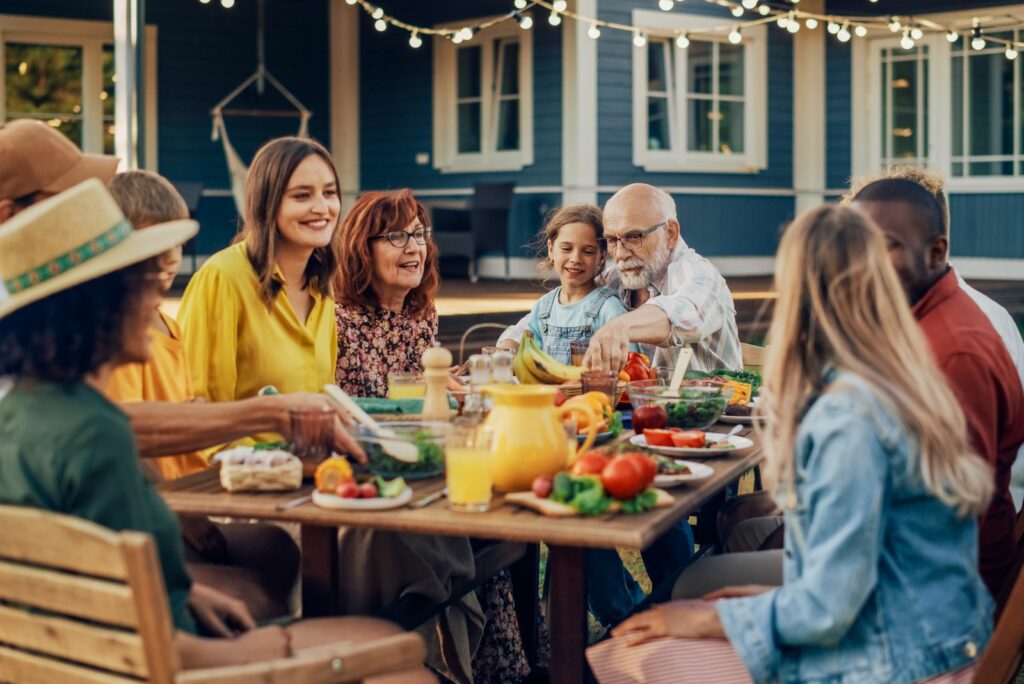 Lächelnde Familie, die draußen sitzt und zu Mittag isst