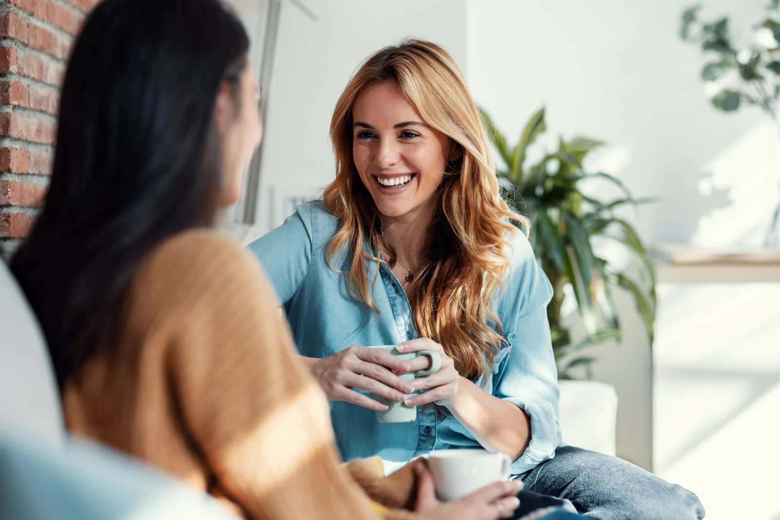 Laechelnde Freundinnen, die sich beim Kaffee unterhalten