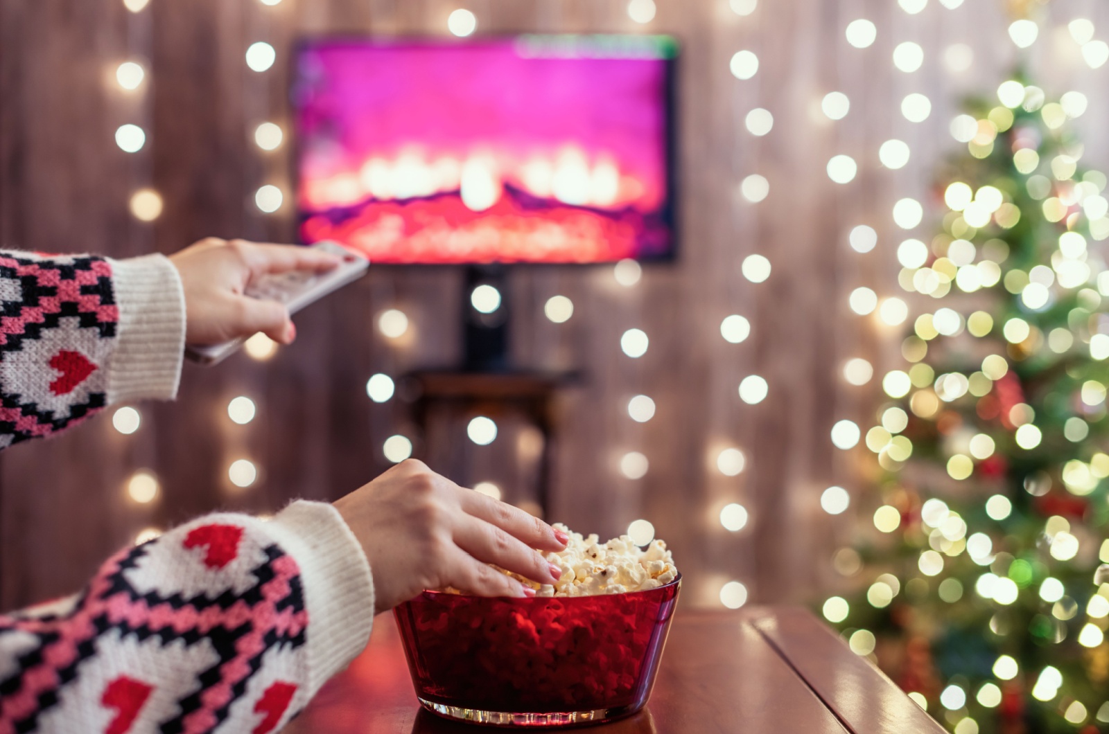 weibliche Hand haelt Fernbedienung und Popcorn