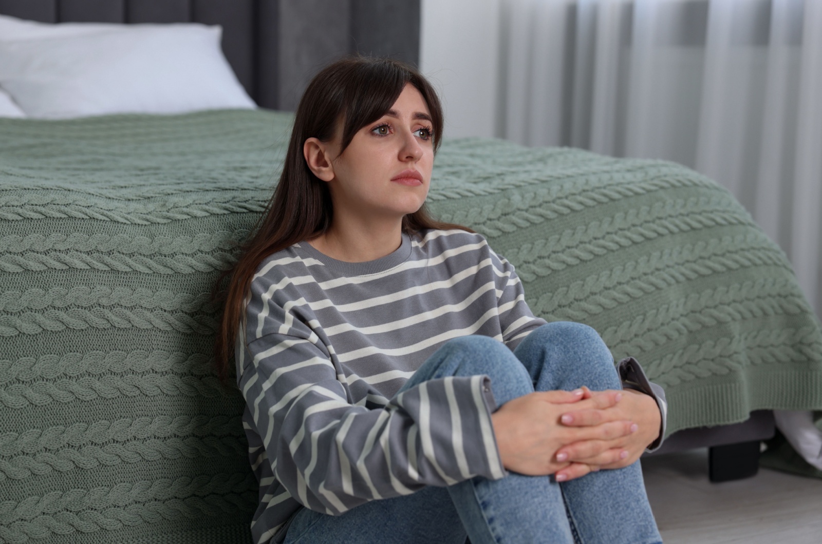 sehr traurige junge Frau sitzt im Schlafzimmer